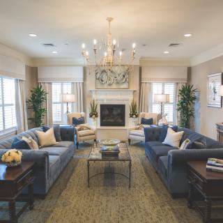 A spacious and elegantly designed living room featuring plush sofas, a central chandelier, and a cozy fireplace.