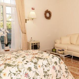 A cozy bedroom with floral bedding, a comfortable sofa, and natural light streaming through the window.