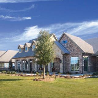 A beautiful suburban brick house with a spacious front yard under a clear blue sky.