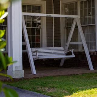 A charming white swing on a porch, inviting relaxation in a cozy outdoor space.