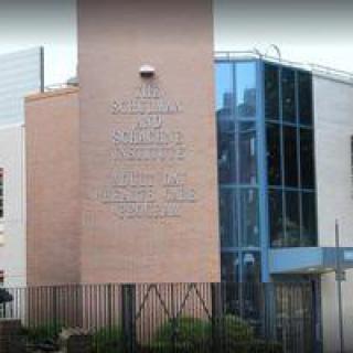 A modern building featuring a brick wall with text and a glass facade.