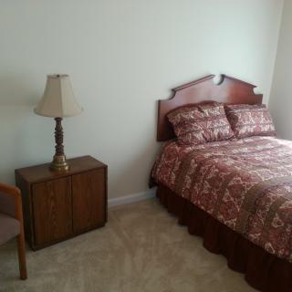 A cozy bedroom with a bed, lamp, and nightstand.