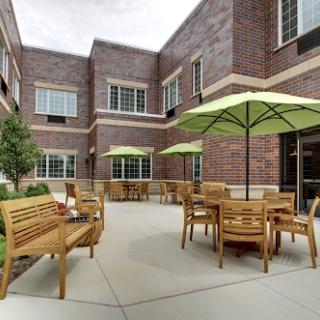 A cozy outdoor courtyard featuring wooden benches and green umbrellas, perfect for enjoying fresh air.