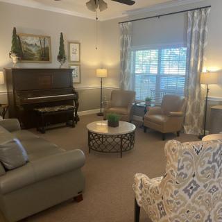 A cozy living room with a piano, comfortable seating, and elegant decor.