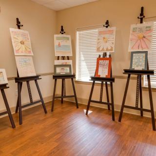 An indoor exhibition showcasing paintings on easels.