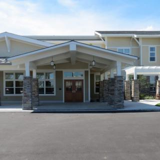 A modern building entrance with a covered walkway and stone pillars.