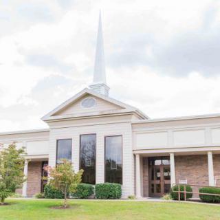 A church building with a prominent steeple and well-maintained landscaping.
