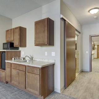 A small kitchen area with wooden cabinets, a sink, and a microwave.