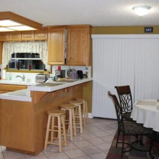 A cozy kitchen and dining area with wooden cabinets, bar stools, and a small dining table.