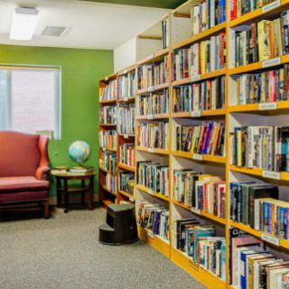 A cozy library corner with bookshelves, a globe, and a comfortable chair.