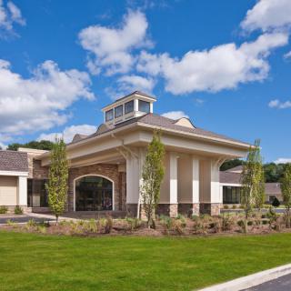 A modern building with a landscaped entrance under a bright blue sky.