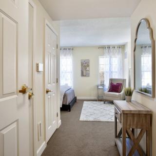 A neatly decorated bedroom with a bed, mirror, and comfortable seating area.