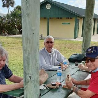 A group of people enjoying a picnic at a park table.