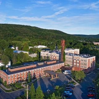 Aerial view of a hospital surrounded by trees and mountains.