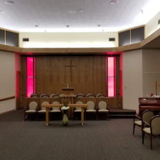 A serene interior view of a church sanctuary featuring wooden paneling and ambient red lighting.