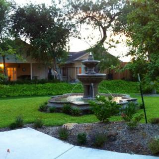 A beautifully landscaped garden featuring a central fountain surrounded by lush greenery.