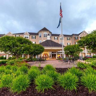 Front view of a hotel with landscaped gardens and an American flag.