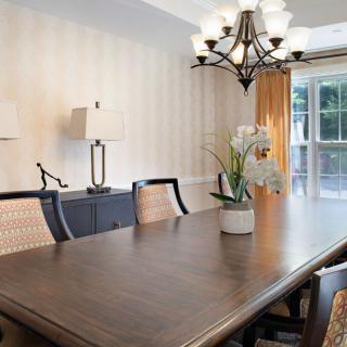 Elegant dining room with a large wooden table, chairs, and a chandelier.