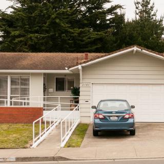 A suburban house with a car parked in the driveway next to a garage.