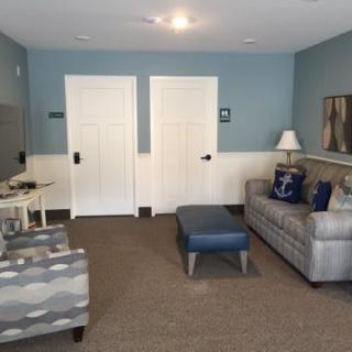 A cozy living room with blue walls, featuring a sofa, armchair, and a lamp.