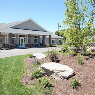 A well-maintained building with landscaped gardens featuring rocks, trees, and grass.