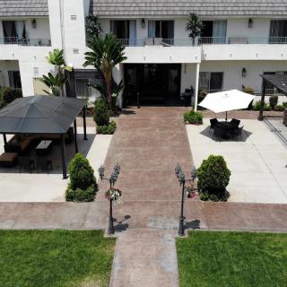 An outdoor patio area with a pathway leading to a building, featuring an umbrella and greenery.
