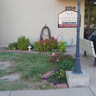 A charming garden area with colorful flowers and a bench outside a building.