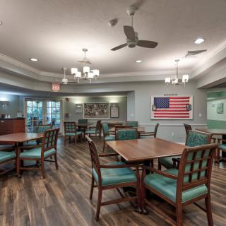 An inviting dining room with wooden floors, set with tables and chairs, featuring a prominent American flag on the wall.