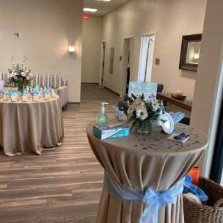 A decorated reception area with tables arranged for an event, adorned with flowers and elegant table settings.