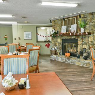 A cozy dining area with tables and chairs, featuring a decorative fireplace.
