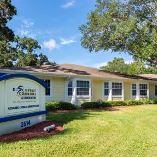A small office building with an outdoor sign and a well-maintained lawn under a clear blue sky.