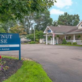A building with a 'Walnut House' sign at the entrance, surrounded by trees and a clear sky.