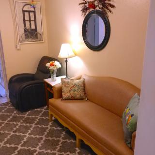 A cozy living room with warm lighting, featuring a sofa, armchair, and decorative elements.
