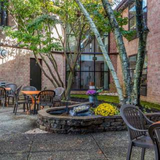 A peaceful courtyard with seating areas and a central fountain surrounded by trees.