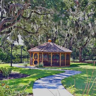A scenic pathway leading to a gazebo surrounded by lush trees and greenery in a park.