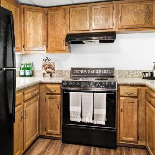 A cozy kitchen with wooden cabinets, a black stove and oven, and rustic decor.