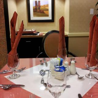 A formal dining table set with intricately folded napkins, glassware, and cutlery.