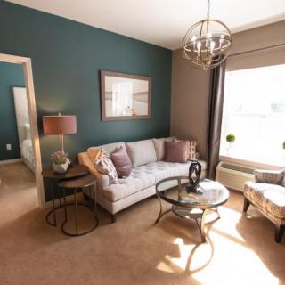 A cozy and stylish living room featuring a teal accent wall, modern furniture, and ample natural light.
