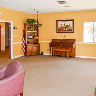 A spacious living room with yellow walls, featuring a piano and comfortable seating.