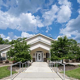 A modern building entrance surrounded by greenery under a cloudy sky.
