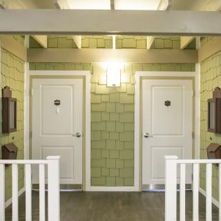 Two adjacent doors in a well-lit interior hallway with green walls.