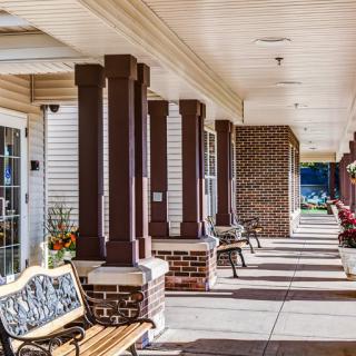 A sunlit veranda with benches and columns along a walkway.