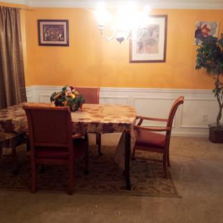 A cozy dining room with a table and chairs, featuring warm lighting and decorative elements.
