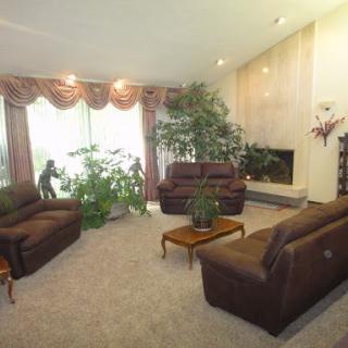 A cozy living room featuring brown sofas, indoor plants, and a fireplace.