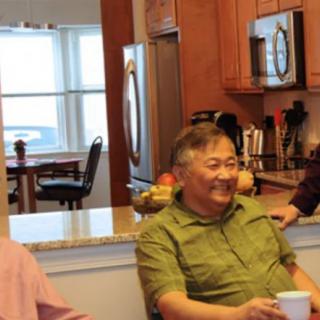 A group of people enjoying a conversation in a kitchen setting.