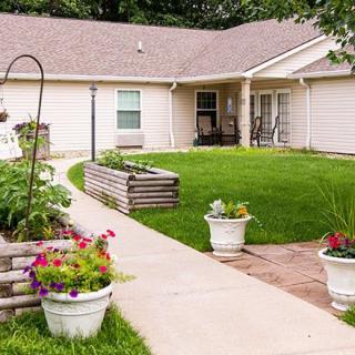 A cozy house with a well-maintained garden and lawn, featuring flower pots and a clear pathway.