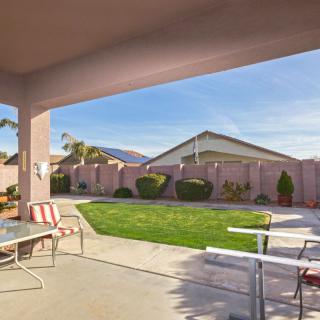 A sunny backyard featuring a patio with outdoor furniture and a well-maintained lawn.