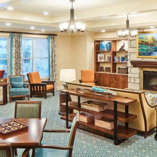 A cozy living room with a fireplace, comfortable seating, and a chessboard.