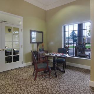 A cozy room with a small table and chairs, featuring large windows and a mirror on the wall.
