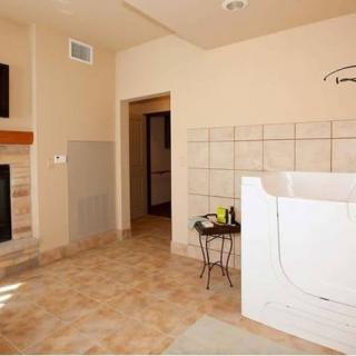A spacious bathroom featuring a bathtub, fireplace, and tile flooring.